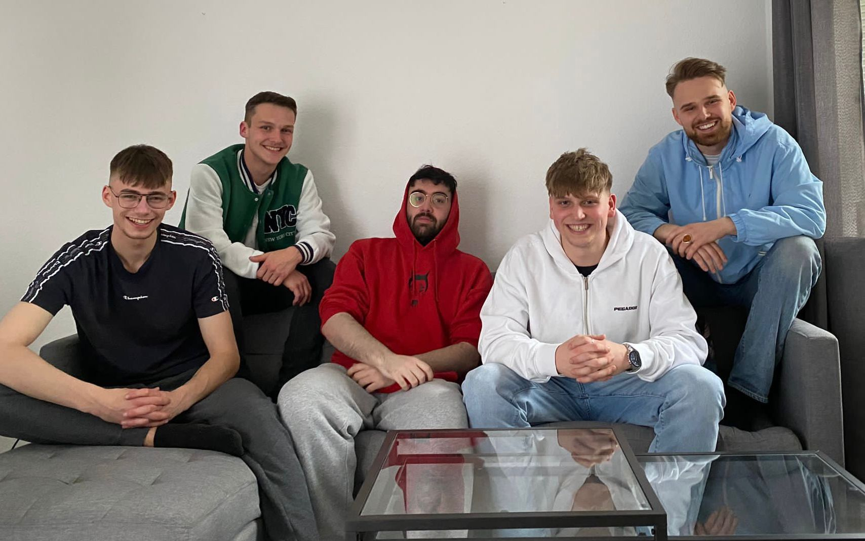 5 junge Männer sitzen auf dem Sofa und posieren